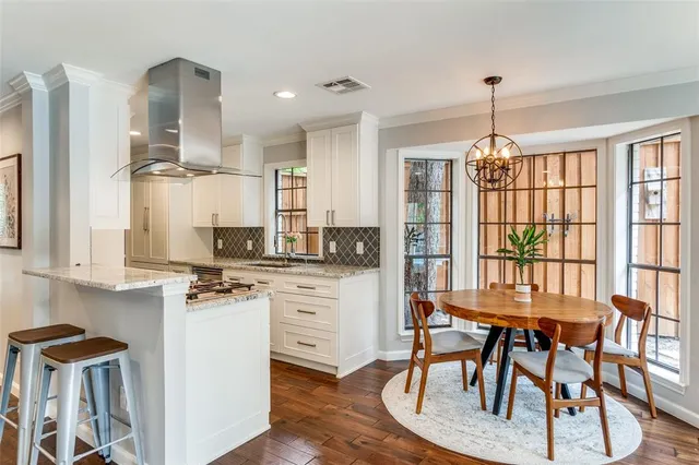 a kitchen with stainless steel appliances kitchen island granite countertop a table chairs sink and cabinets