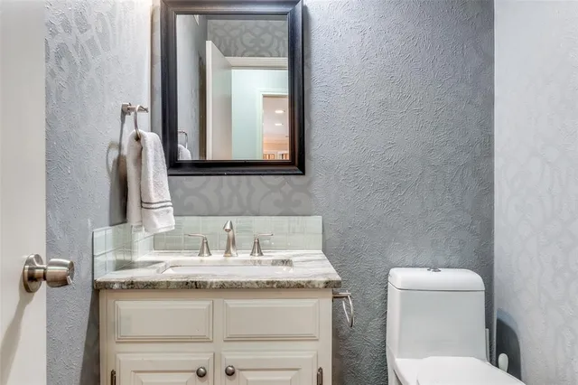 a bathroom with a granite countertop toilet sink and mirror