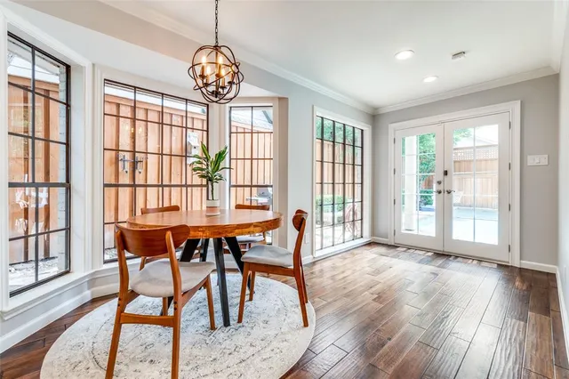 a dining room with wooden floor a chandelier a glass table and chairs