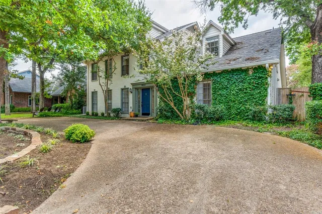 a front view of a house with garden and trees