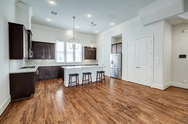 a large kitchen with stainless steel appliances granite countertop a stove and a wooden floors