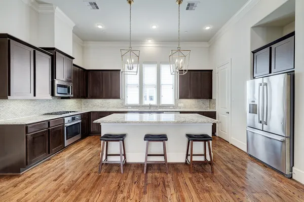 a kitchen with stainless steel appliances granite countertop a refrigerator a stove a sink and a microwave