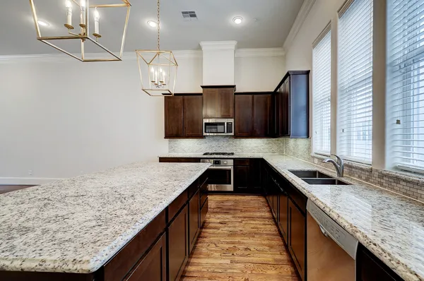 a kitchen with granite countertop kitchen island stainless steel appliances a sink stove and cabinets