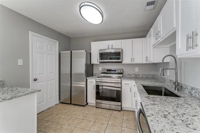 a kitchen with stainless steel appliances granite countertop a stove a sink and a microwave