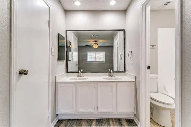 a bathroom with a granite countertop sink a toilet a mirror and shower