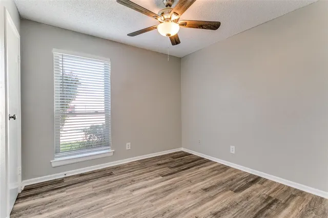 a view of empty room with wooden floor and fan