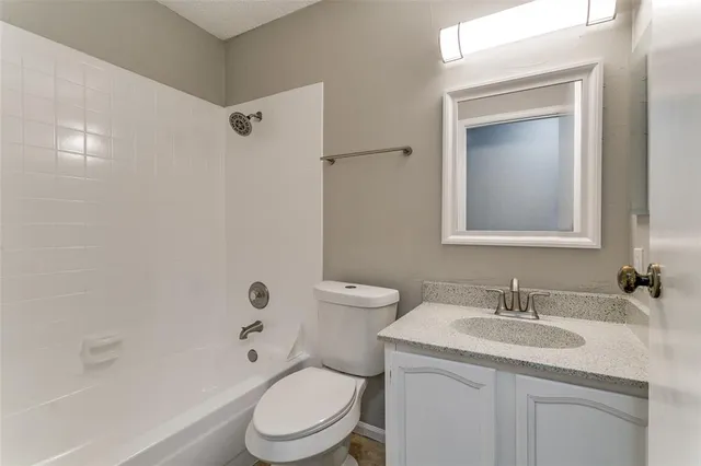 a bathroom with a granite countertop sink a toilet and shower