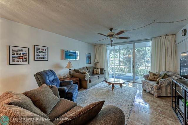 a living room with furniture ceiling fan and a large window