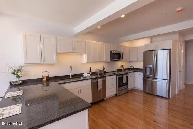 a kitchen with granite countertop a refrigerator sink and wooden cabinets