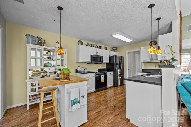 a kitchen with kitchen island a stove a sink a kitchen island and chairs with wooden floor