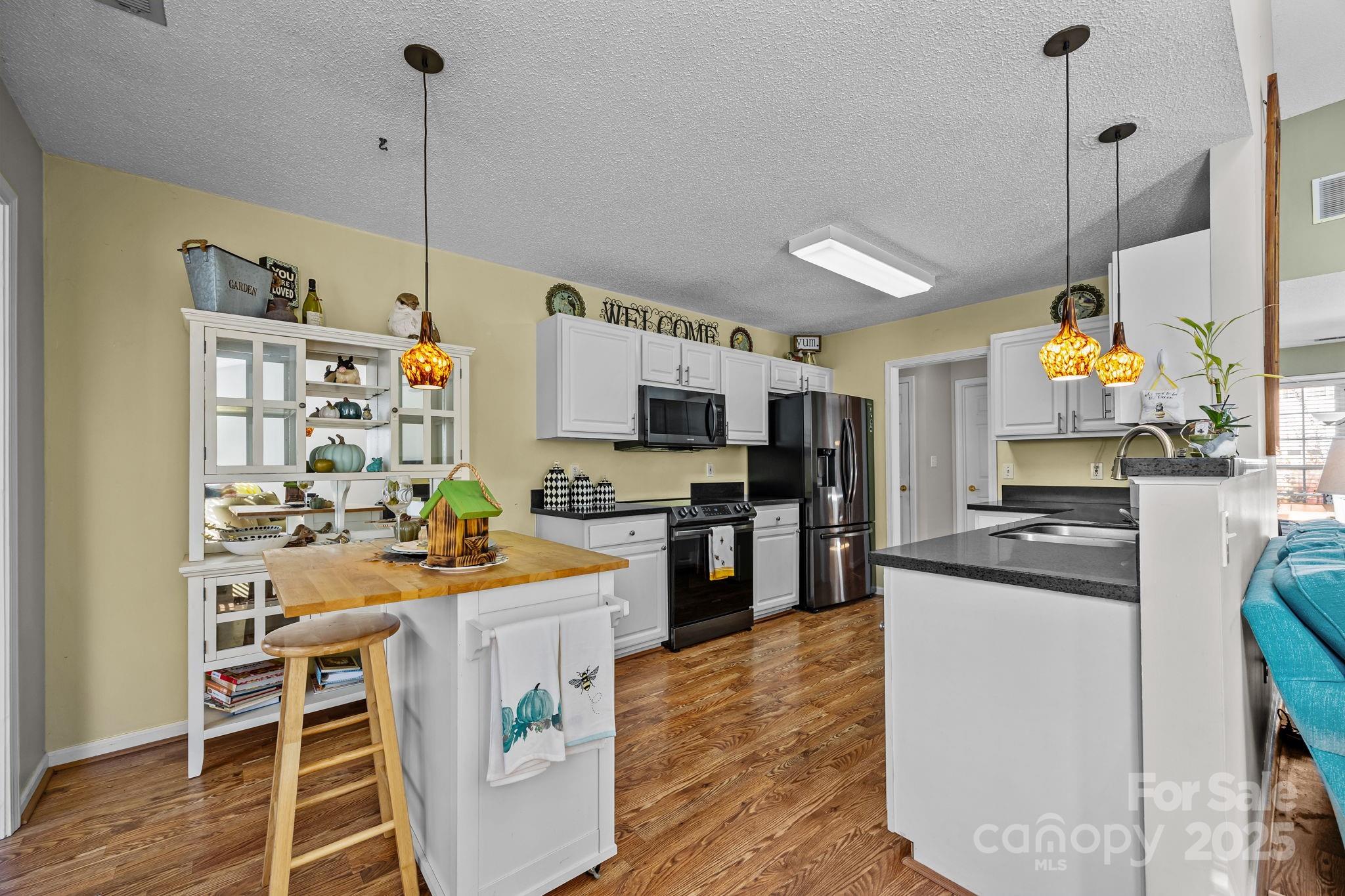 255 Stonehollow Road Fletcher, NC 28732 - Photo 11 of 32 a kitchen with kitchen island a stove a sink a kitchen island and chairs with wooden floor