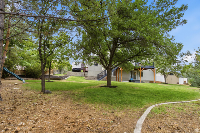 11882 Pond Ridge Drive Draper, UT 84020 - Photo 44 of 49 Sloping lawn with mature trees, a concrete border, and a raised wooden deck