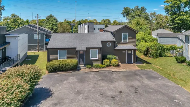 a view of a house with a small yard and a large tree