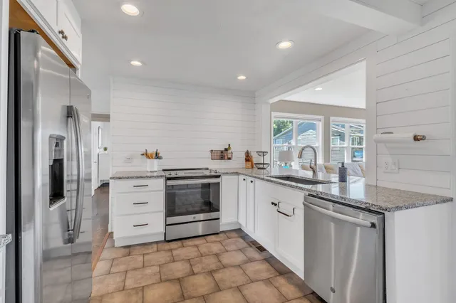 a kitchen with stainless steel appliances granite countertop a refrigerator and a stove top oven