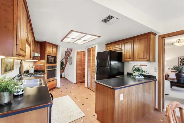 a kitchen with stainless steel appliances granite countertop a refrigerator a stove and a wooden cabinets