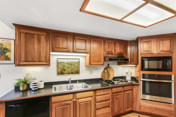 a kitchen with granite countertop wooden cabinets a stove top oven a sink and dishwasher