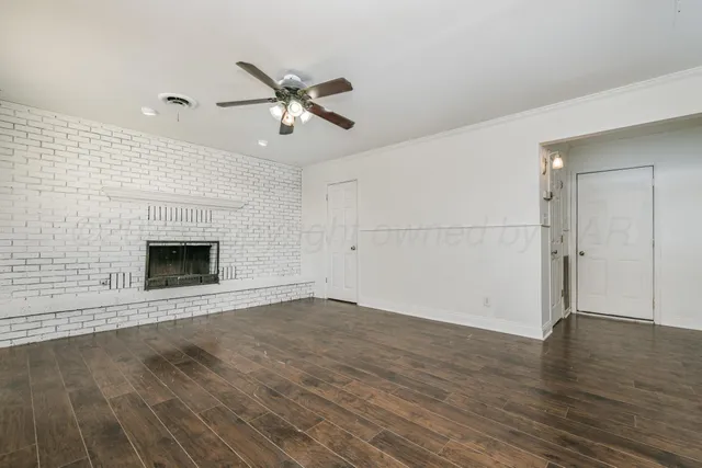 an empty room with wooden floor a ceiling fan and windows