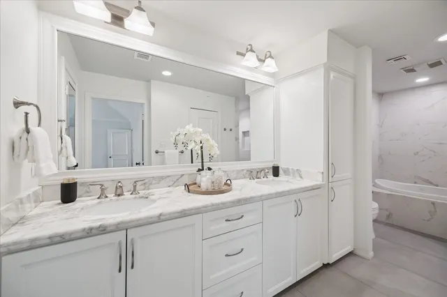 a bathroom with double vanity sinks a toilet a mirror and vanity