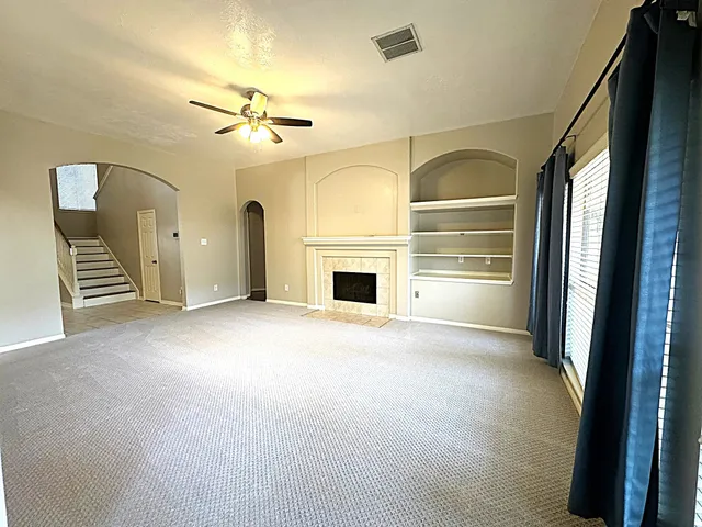 an empty room with windows and fireplace