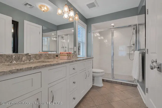 a bathroom with a granite countertop sink toilet a large mirror a shower and a bathtub
