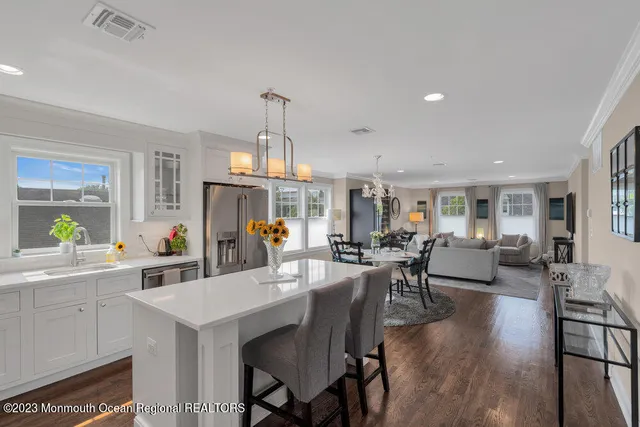 a view of a dining room and livingroom with furniture wooden floor a rug a flat screen tv a painting and a chandelier