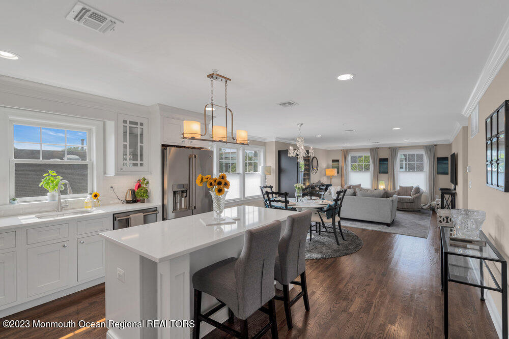 308 Morris Avenue, Unit A Spring Lake, NJ 07762 - Photo 5 of 37 a view of a dining room and livingroom with furniture wooden floor a rug a flat screen tv a painting and a chandelier