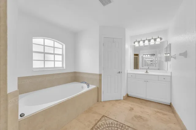 a bathroom with a tub a sink and a large mirror