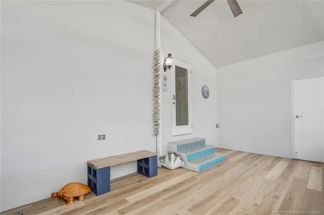 a view of an empty room with wooden floor and window