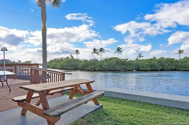 a view of a lake with couches chairs and wooden fence