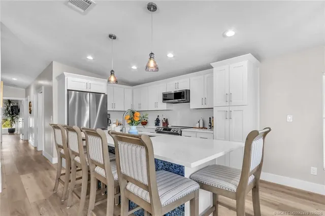 a kitchen with stainless steel appliances kitchen island granite countertop a refrigerator a stove a sink a dining table and chairs