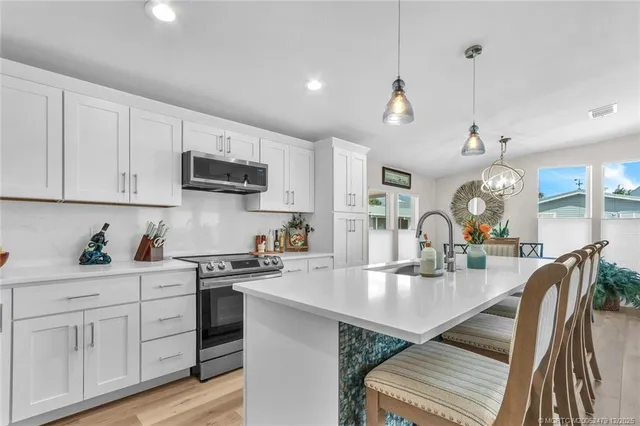 a kitchen with white cabinets appliances and dining table