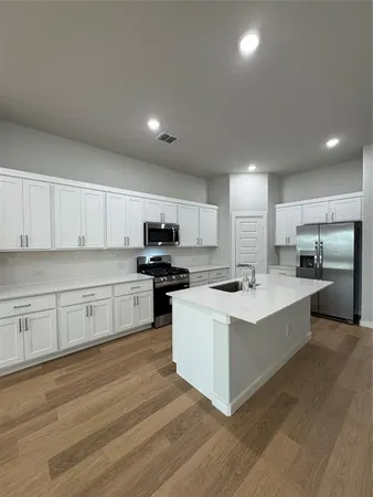a large kitchen with stainless steel appliances and white cabinets