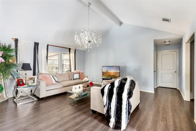 a living room with furniture a chandelier and wooden floor