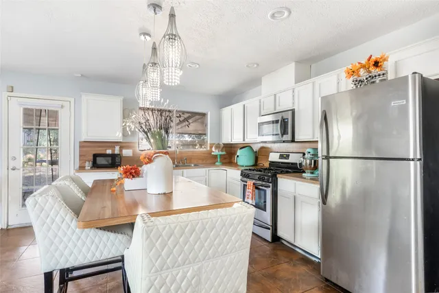 a kitchen with stainless steel appliances granite countertop a refrigerator a stove a sink dishwasher a dining table and chairs with wooden floor