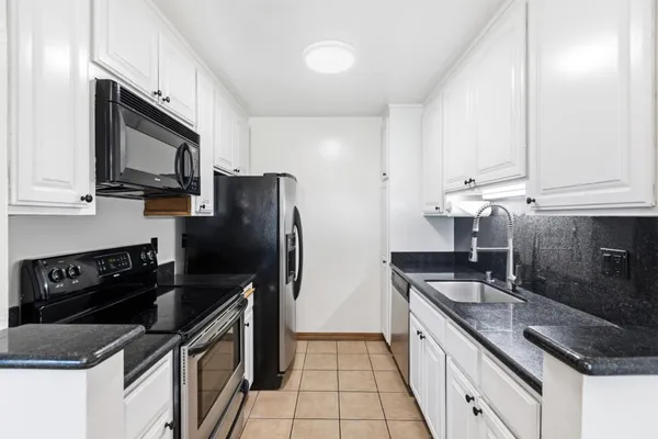 a kitchen with granite countertop a sink stove and refrigerator
