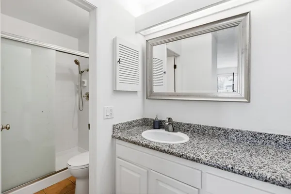 a bathroom with a granite countertop sink toilet and mirror