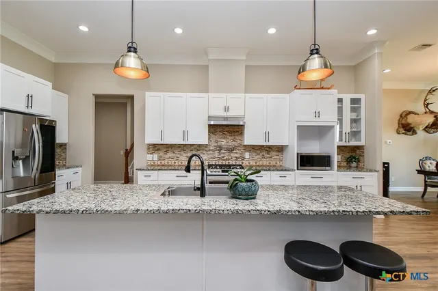 a kitchen with stainless steel appliances granite countertop a sink a stove a refrigerator and a microwave