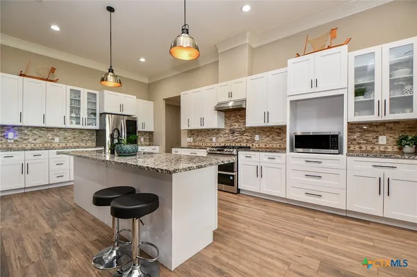 a kitchen with a refrigerator a stove cabinets and wooden floor