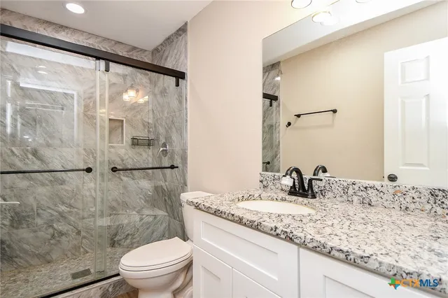 a bathroom with a granite countertop sink toilet and shower