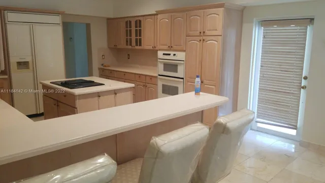 a kitchen that has a sink a stove and chair