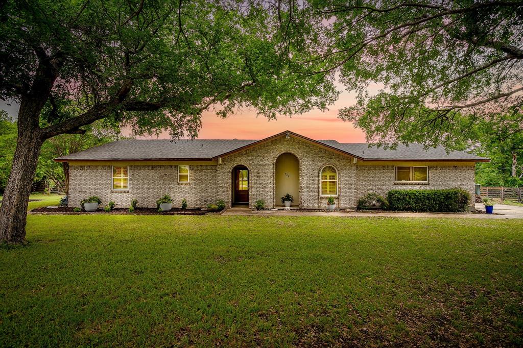 Brick exterior residence with a prominent arched entry and an expansive front lawn