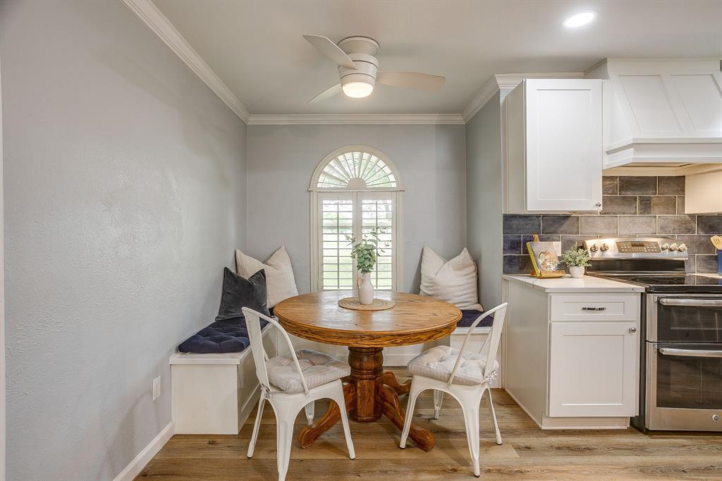 408 Jeri Ridge Road Willow Park, TX 76087 - Photo 11 of 38 Kitchen dining nook featuring a built-in bench, arched window with plantation shutters, wood-finish flooring, white cabinetry, and stainless steel appliances