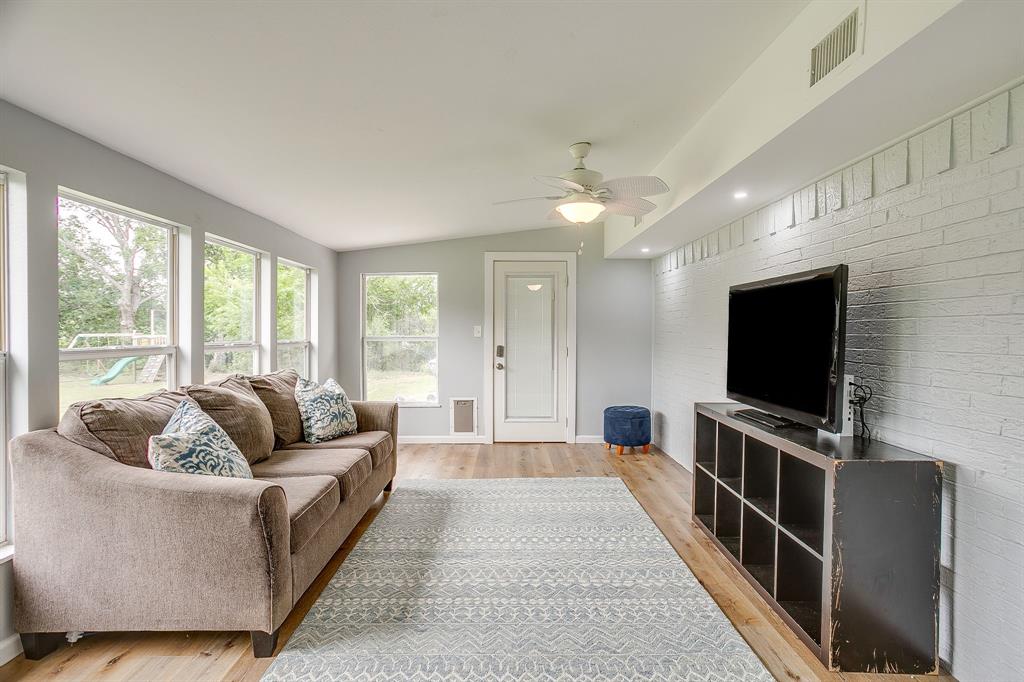 408 Jeri Ridge Road Willow Park, TX 76087 - Photo 18 of 38 Living area featuring wood-finish flooring, a white painted brick accent wall, and multiple large windows