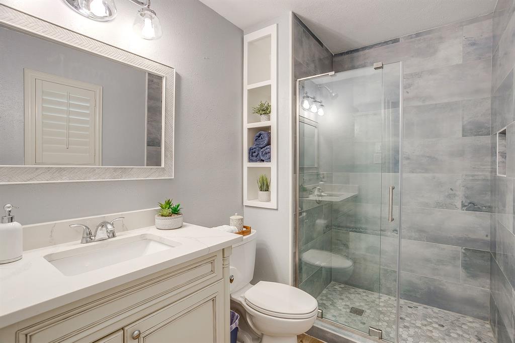 408 Jeri Ridge Road Willow Park, TX 76087 - Photo 22 of 38 Walk-in shower with glass enclosure, textured gray tile walls, and a hexagonal tile floor