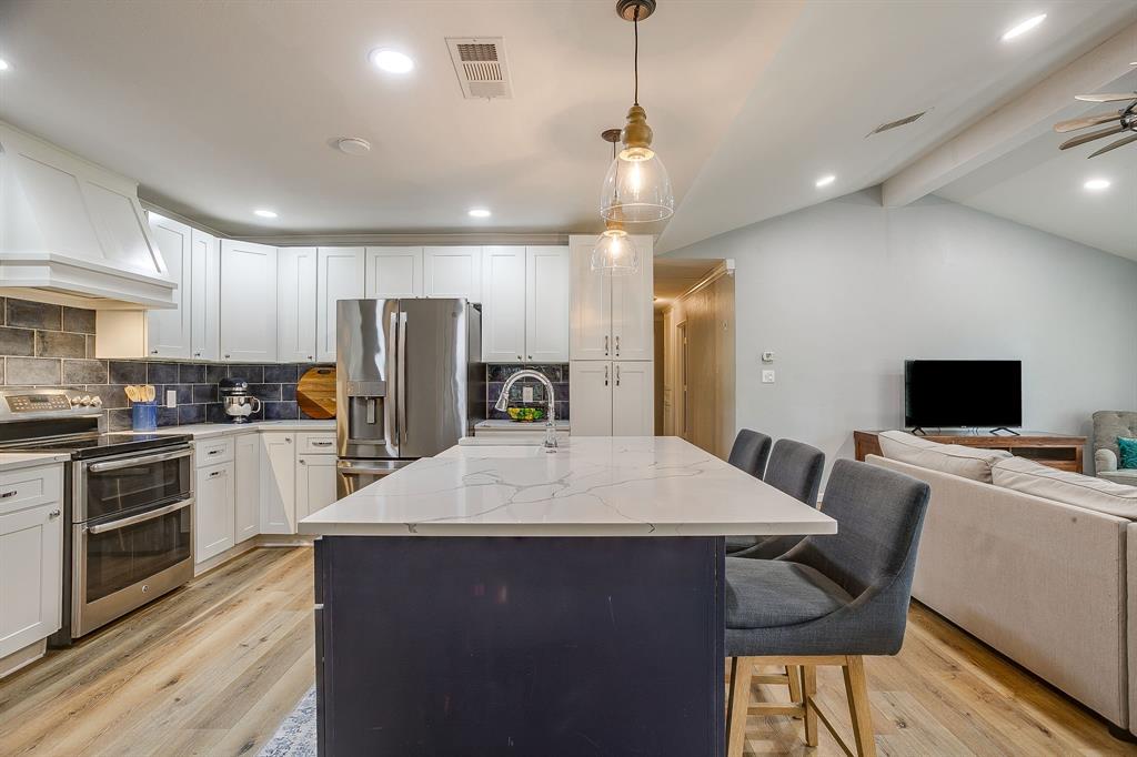 408 Jeri Ridge Road Willow Park, TX 76087 - Photo 8 of 38 Modern kitchen featuring a large island with seating, stainless steel appliances, white cabinetry, and wood-finish flooring