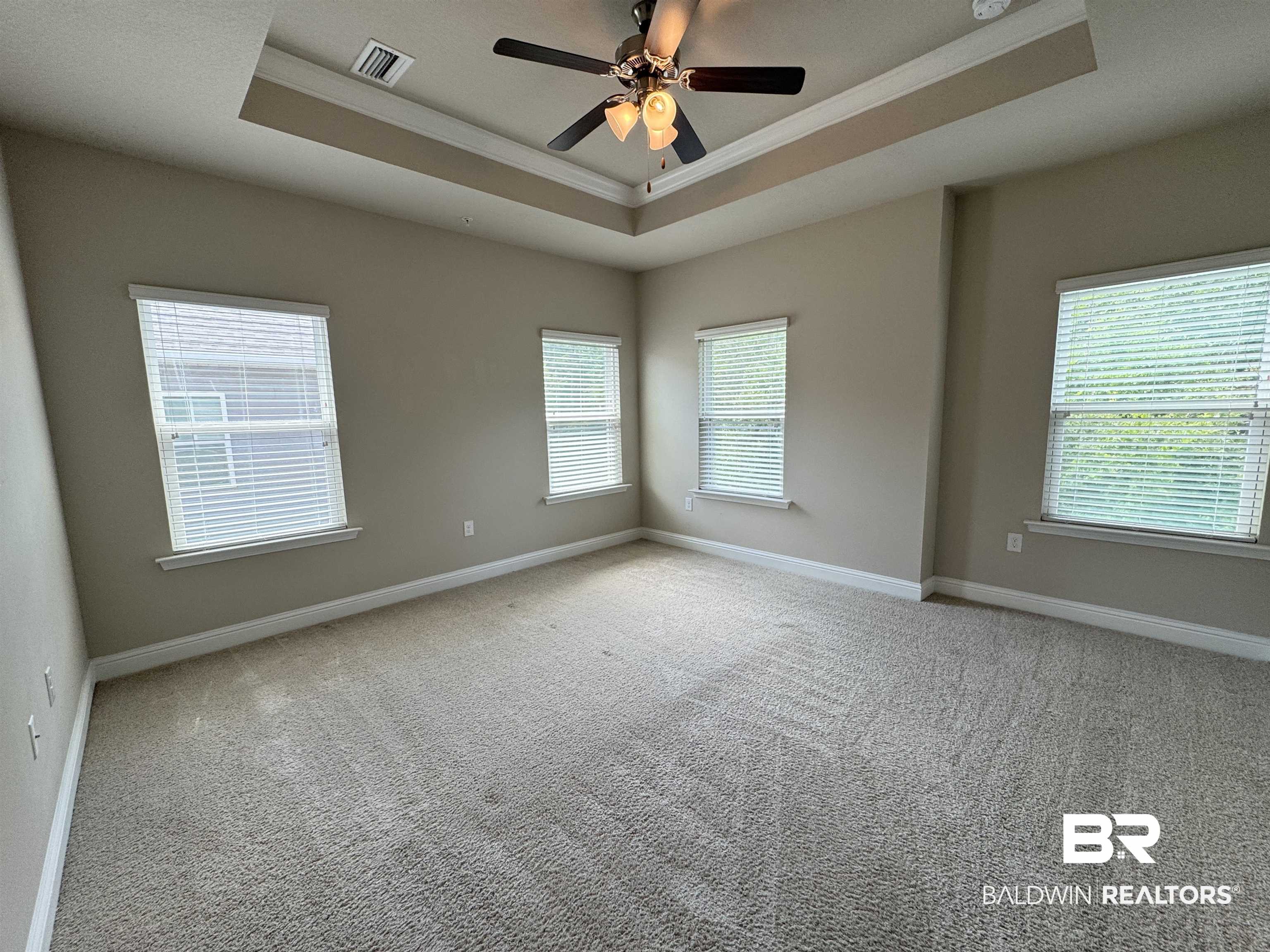6811 Spaniel Drive, Unit C Daphne, AL 36527 - Photo 5 of 33 Unfurnished room with a tray ceiling, crown molding, baseboards, light carpet, and a ceiling fan