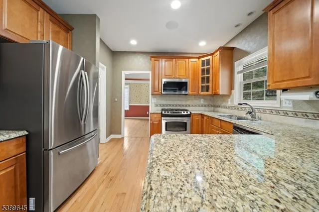 a kitchen with stainless steel appliances granite countertop a refrigerator a stove and a sink