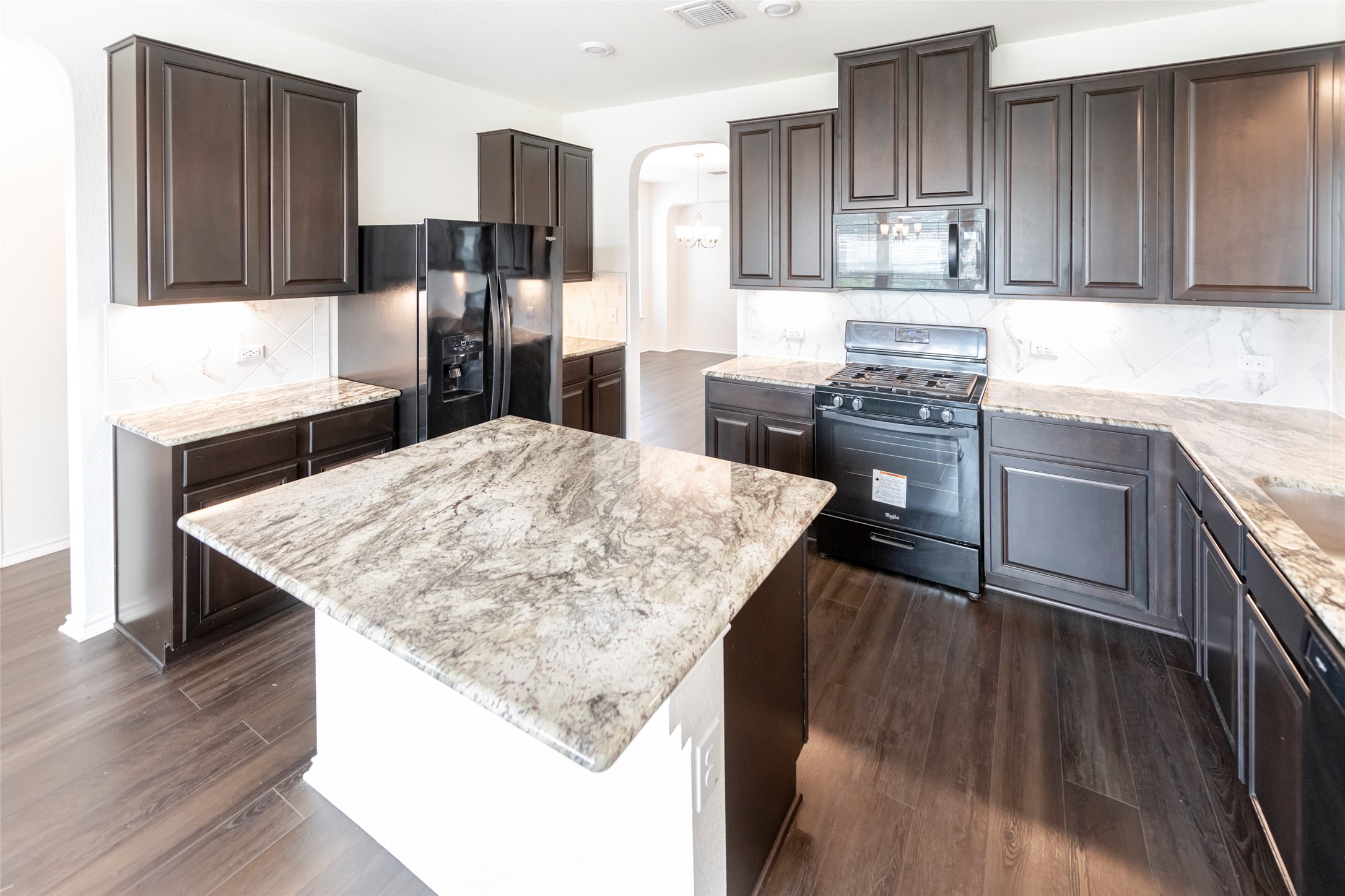 1101 Arbor Acres Loop Leander, TX 78641 - Photo 4 of 19 a kitchen with stainless steel appliances kitchen island granite countertop a kitchen island a hardwood floor and wooden cabinets