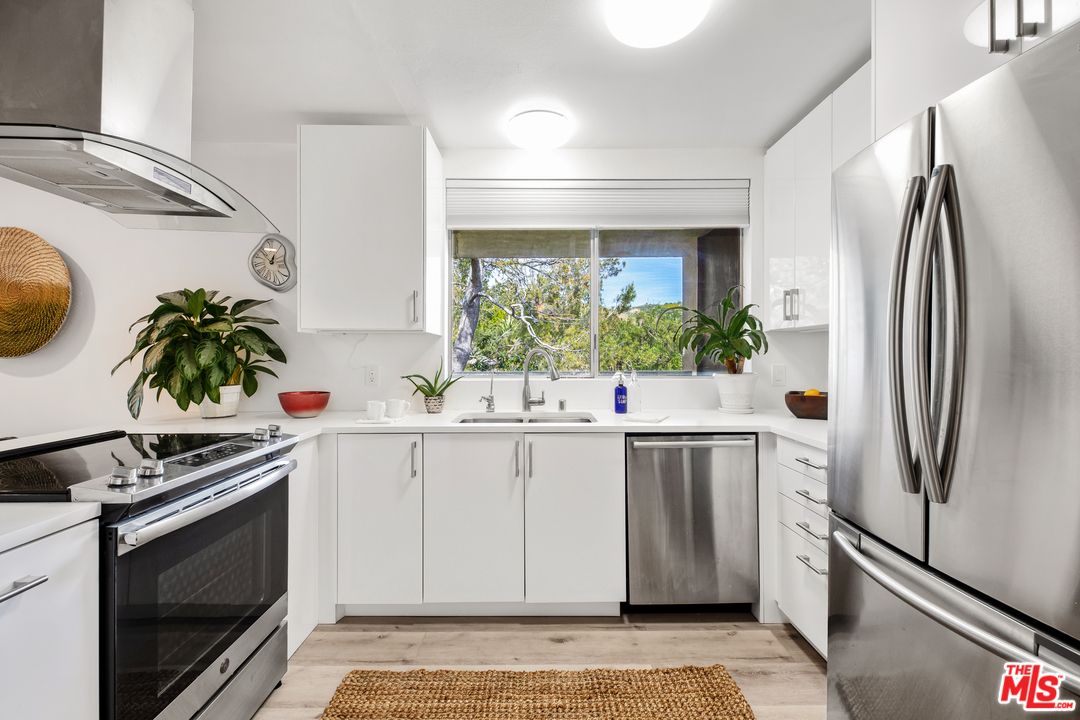 8303 Raintree Circle Culver City, CA 90230 - Photo 9 of 26 a kitchen with stainless steel appliances a white cabinets and a potted plant