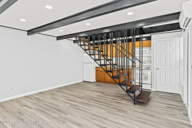 a view of an empty room with wooden floor and stairs